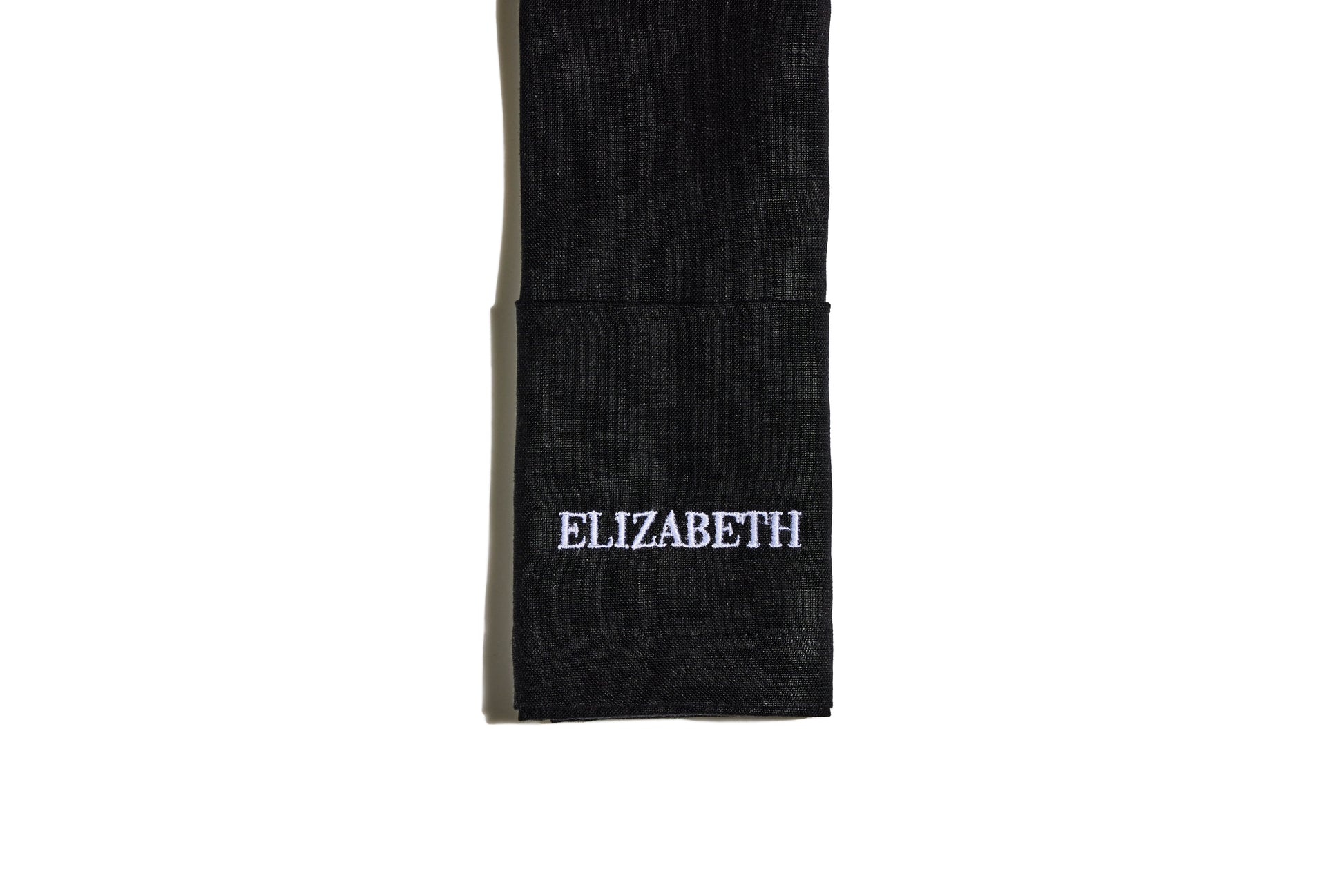 Black linen napkin with white embroidered name Elizabeth in block capitals