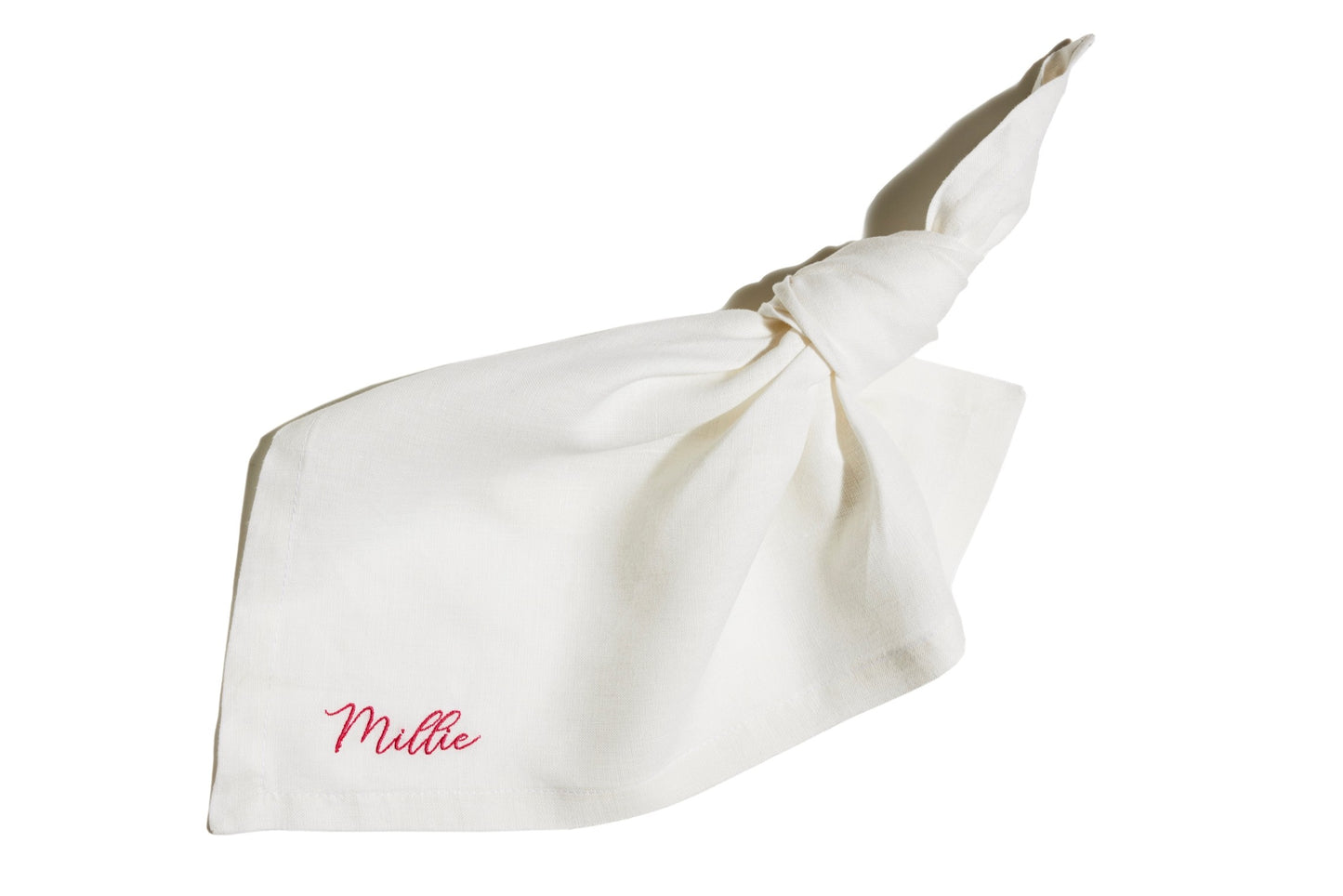 White linen napkin with knotted corner, featuring custom name embroidery in pink thread