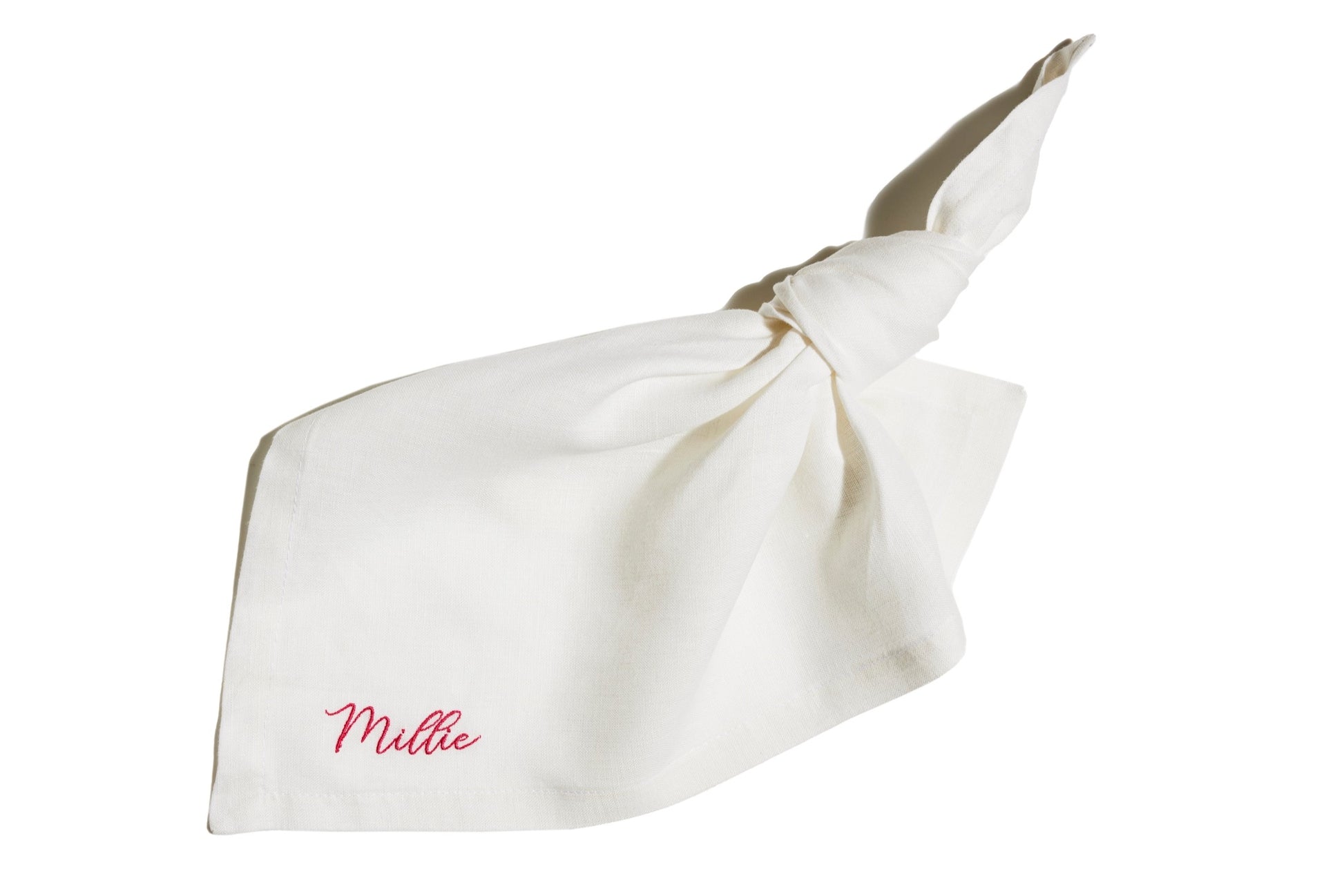White linen napkin with knotted corner, featuring custom name embroidery in pink thread