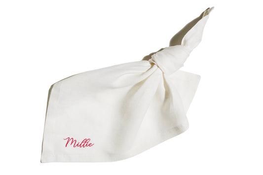 White linen napkin with knotted corner, featuring custom name embroidery in pink thread