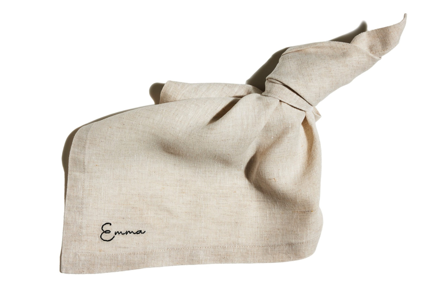 Sand linen napkin with knotted corner, featuring custom name embroidery in black thread