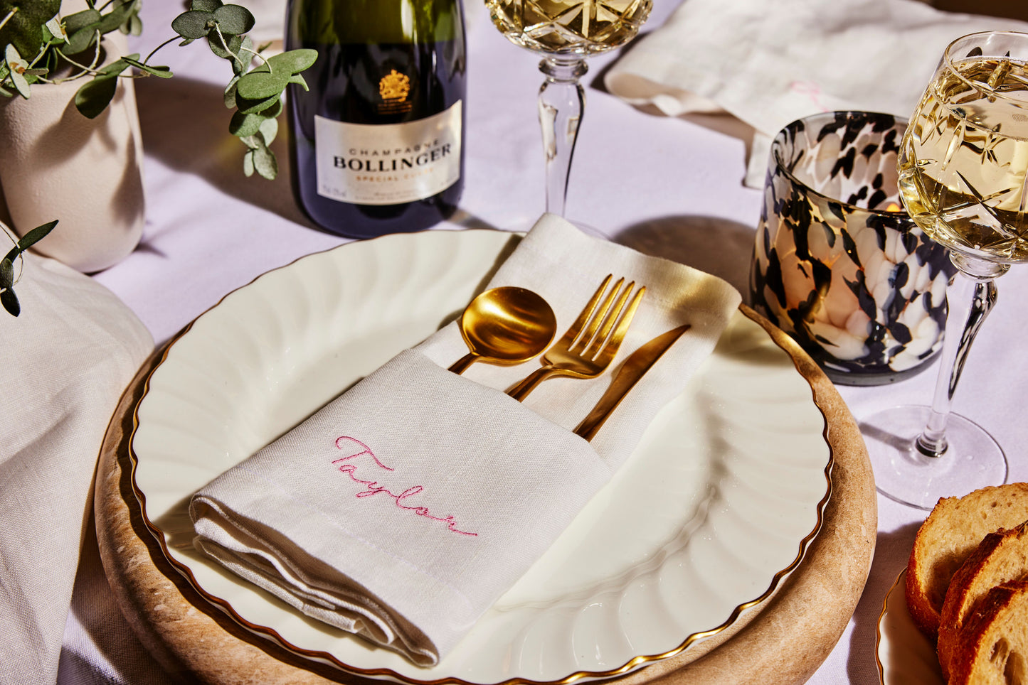 Champagne table setting with personalised linen napkin and gold cutlery for an elegant celebration.